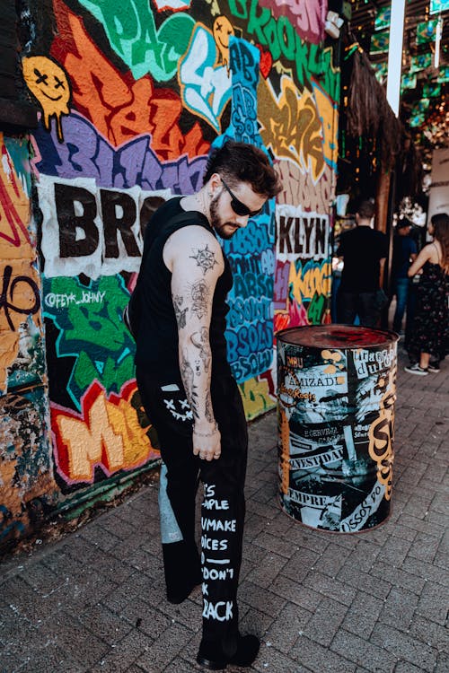 Man in Tank Top Standing Beside a Wall Art