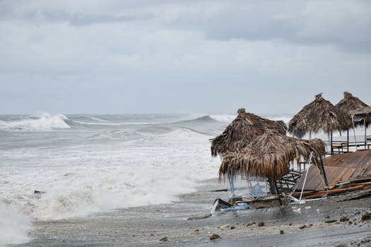 Dramatic waves crash on a Batumi beach with rustic huts under overcast skies.