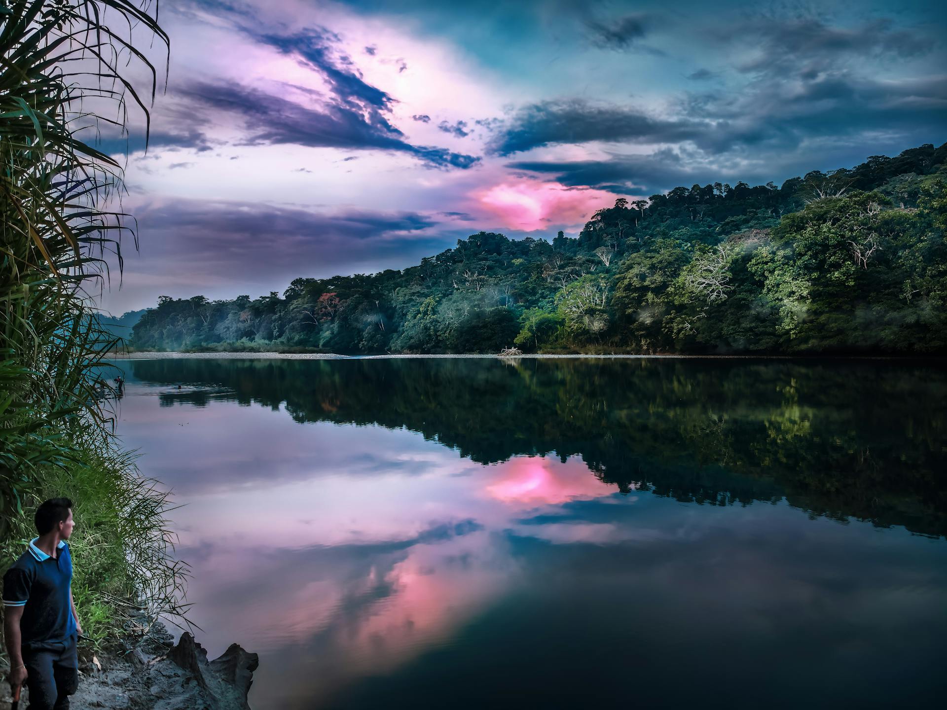 Peaceful river view at sunset in Ecuador's lush rainforest, reflecting vibrant skies.