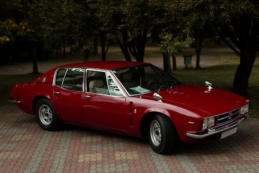 Classic red Iso Rivolta car displayed outdoors in Minsk, Belarus park setting, exuding retro charm.