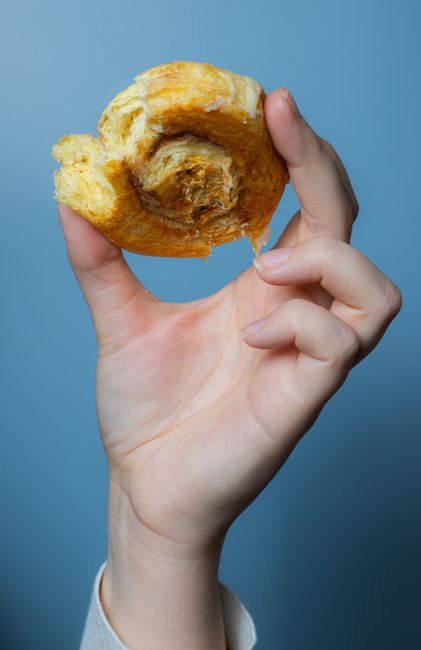 Close-up view of a hand holding a delicious pastry against a blue background.