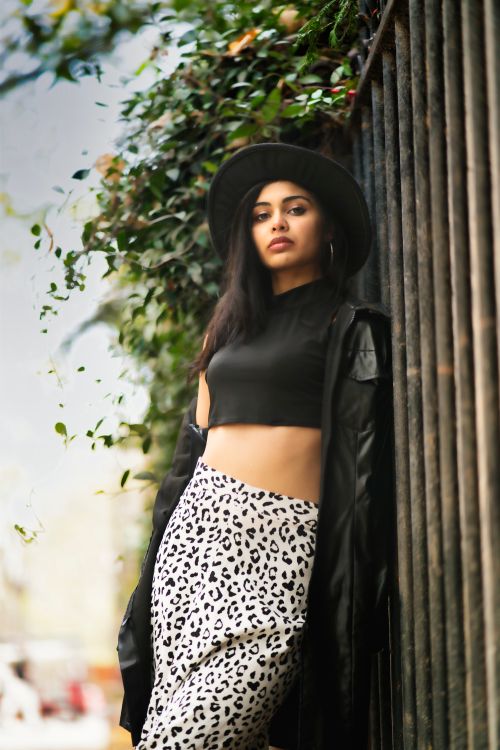 Free Fashionable woman leaning against a fence outdoors, showcasing modern style. Stock Photo