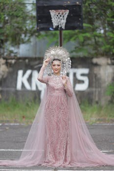 Asian woman in a beautiful bridal gown and crown standing on a basketball court.