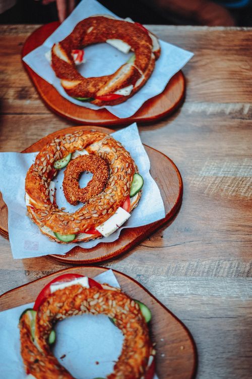 Free Savory Turkish simit served with fresh cucumber and cheese on a wooden table. Stock Photo