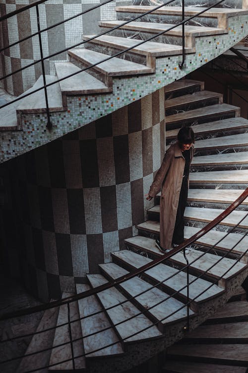 Photo of a Woman in a Coat Standing on the Stairs