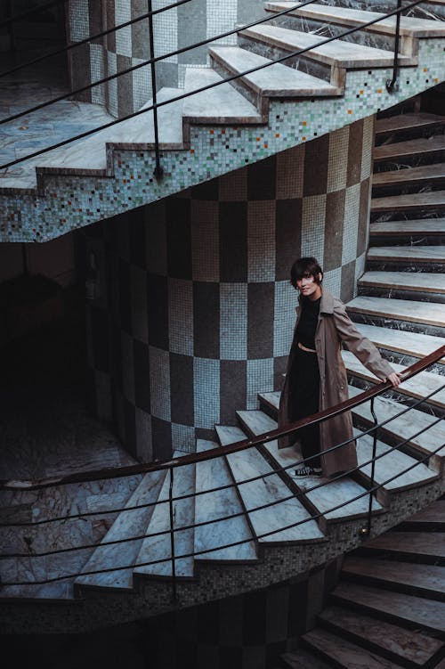 Woman in Coat Posing on Swirling Staircase