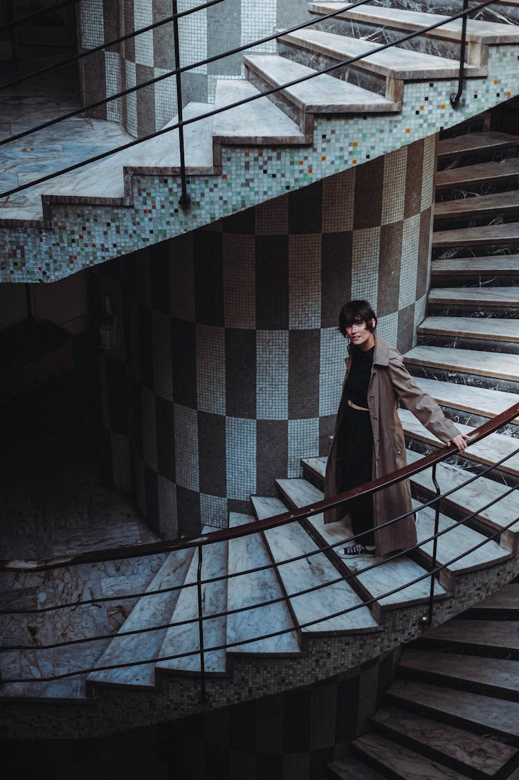 Woman In Coat Posing On Swirling Staircase