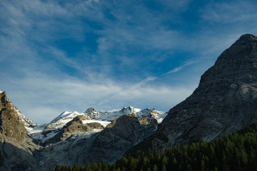 Breathtaking view of snow-covered rocky mountains against a bright blue sky.