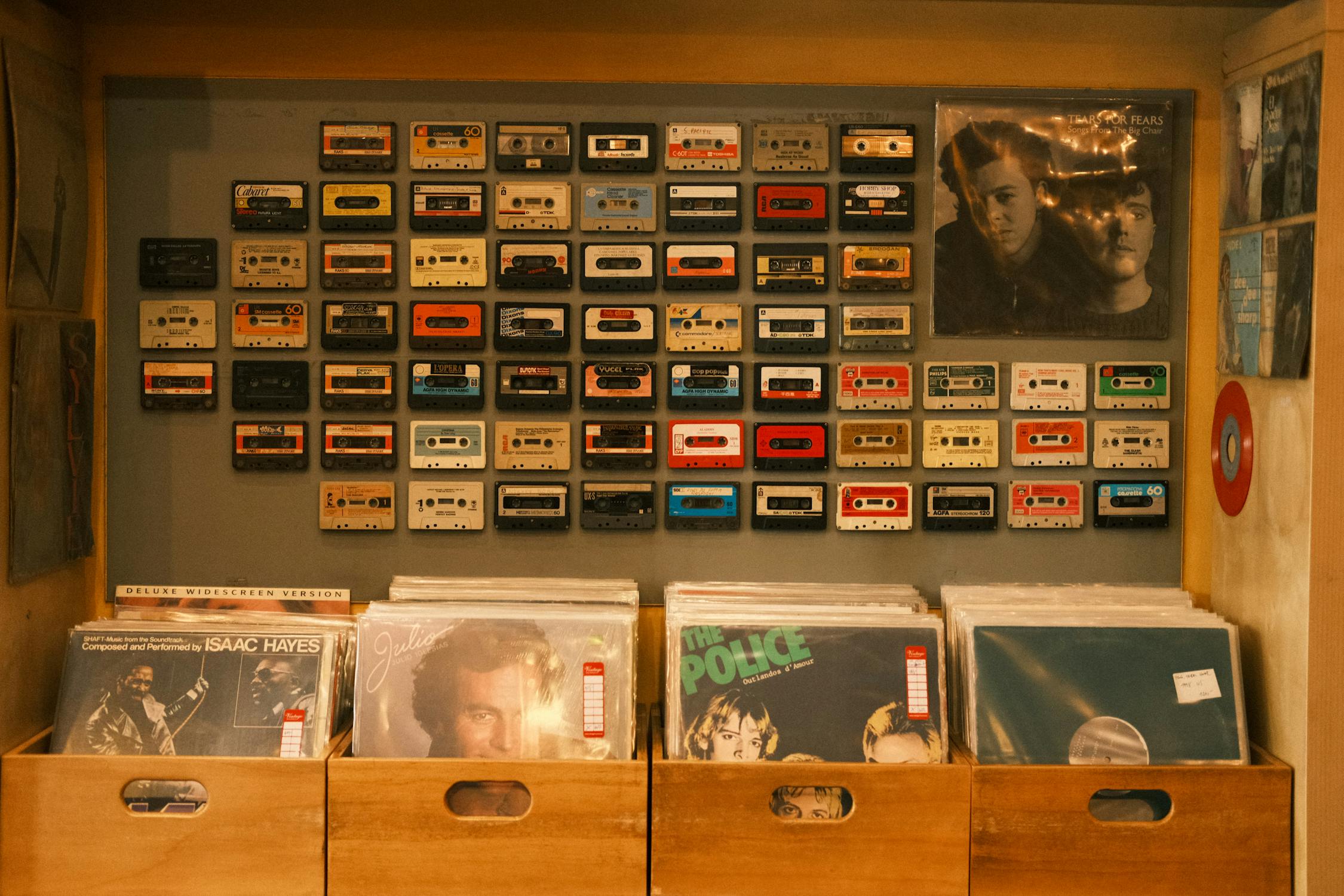 Vinyl Records and a Wall Decorated with Cassettes · Free Stock Photo
