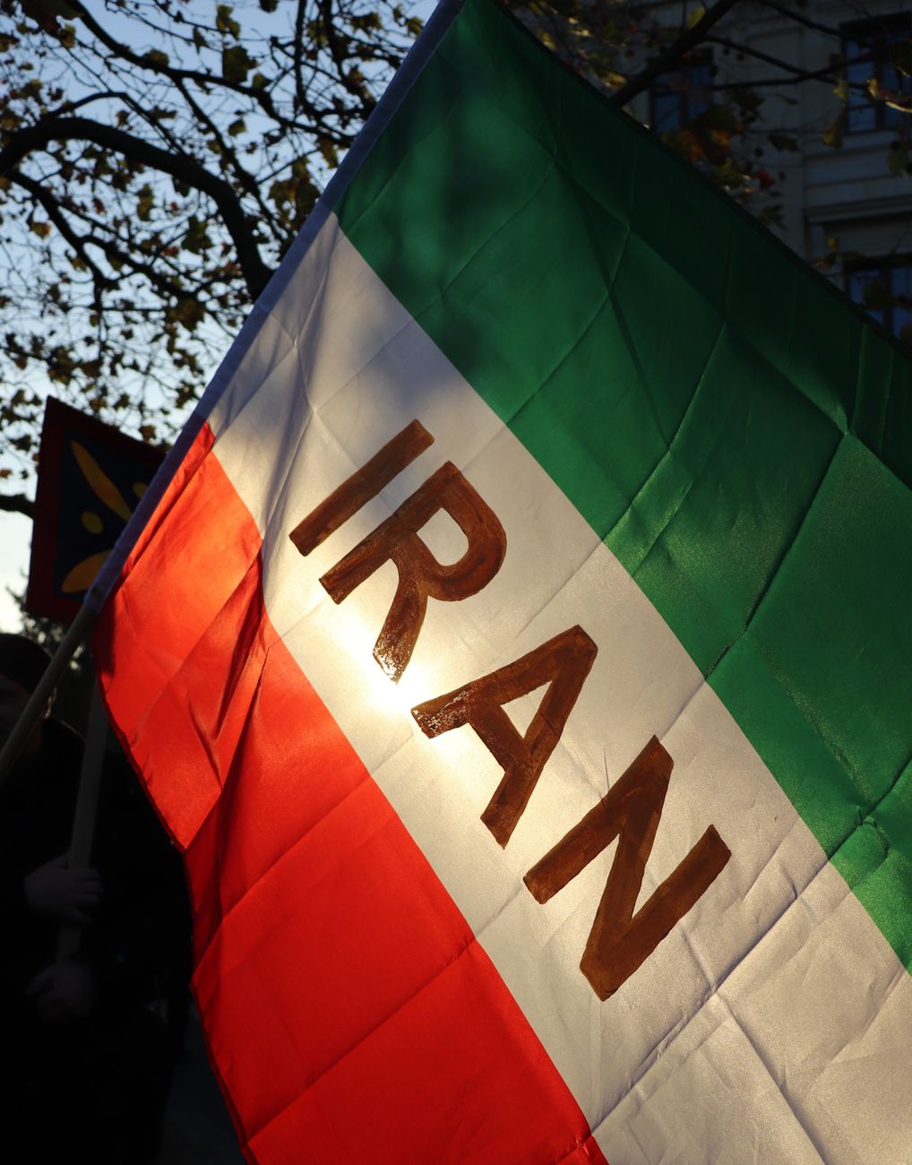 Iranian flag flying outdoors as US officials weigh another round of strikes and Tehran resists terms on uranium and shipping.