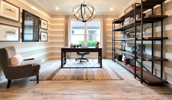 Elegant home office with modern lighting, framed art, and wooden furniture creating a serene workspace.