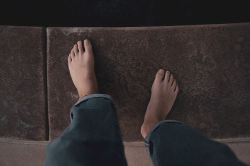 Free A person's bare feet stand on textured concrete in a first-person view. Stock Photo