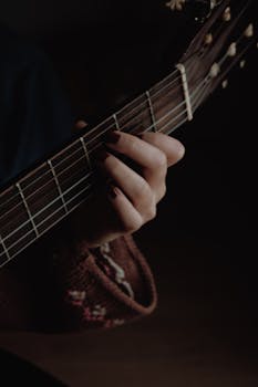Detailed shot of a hand playing an acoustic guitar. Perfect for music-themed projects.