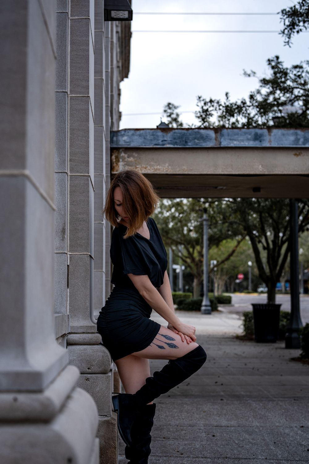 A Woman in Black Dress and Boots Standing on the Street · Free Stock Photo