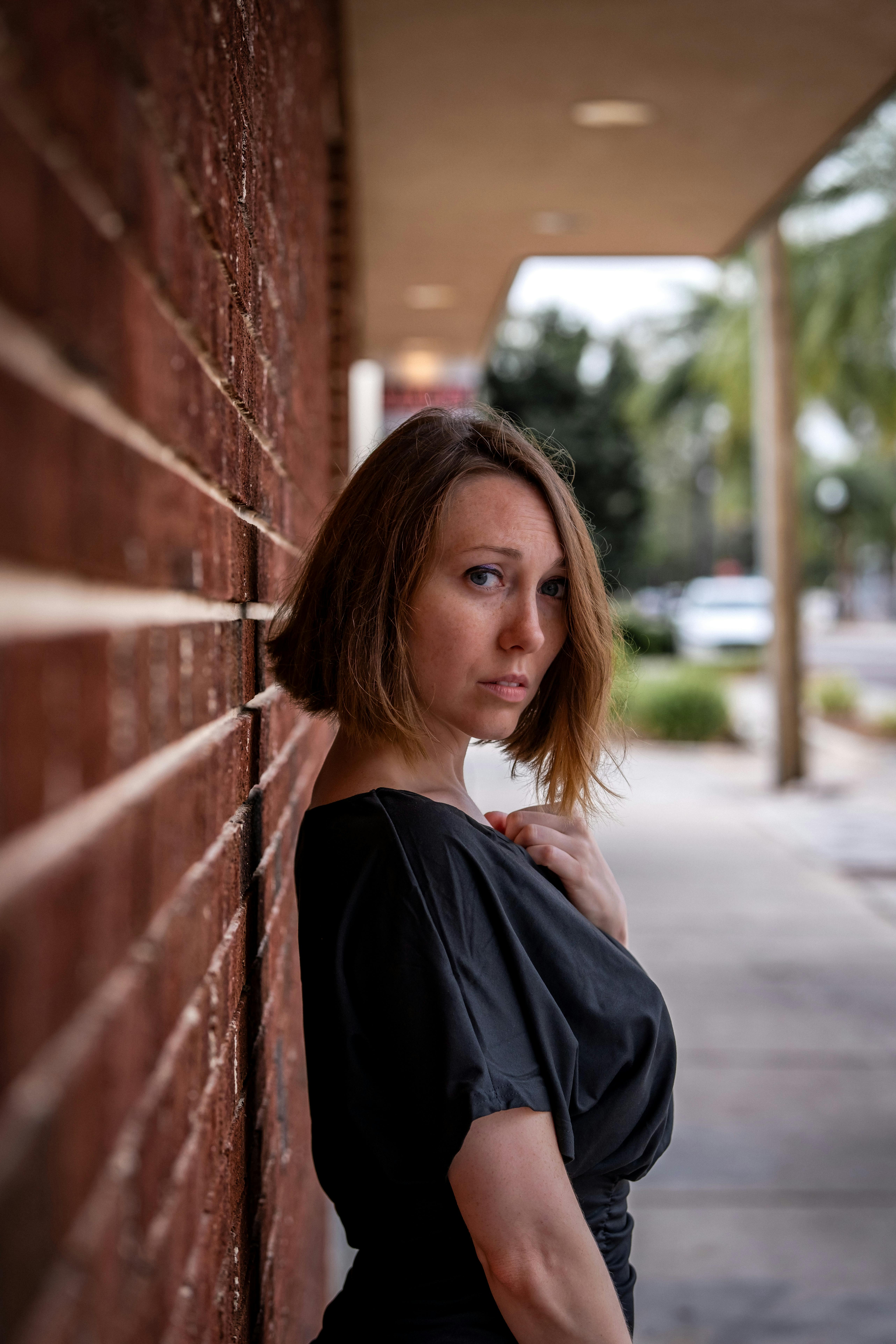 a woman posing near a brick wall