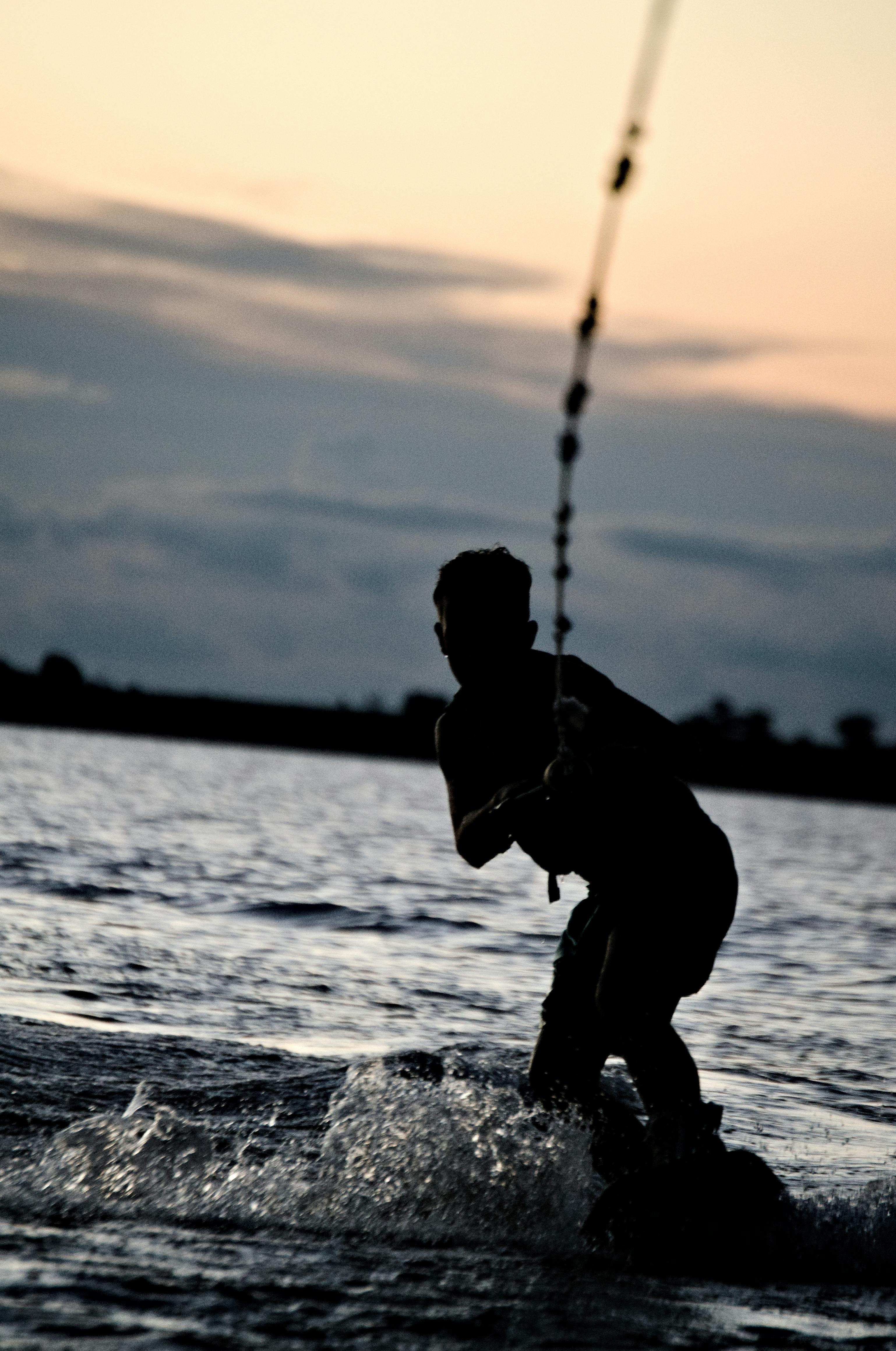 silhouette of man wakeboarding on sunset