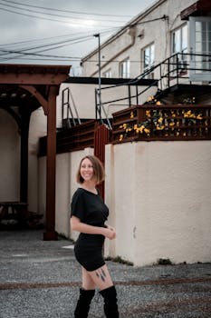 Urban setting portrait of a smiling woman in black, showcasing fashion in a casual environment.