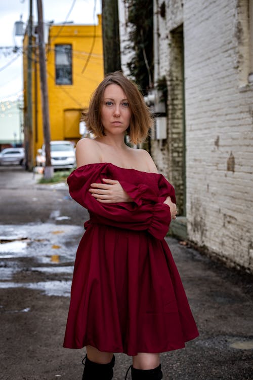 A Woman in Red Off Shoulder Dress Standing on the Street with Her Arms Crossed