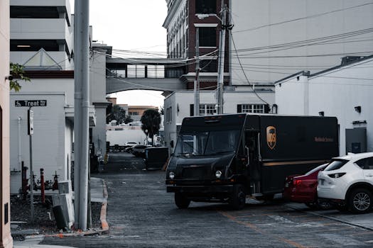 A UPS truck parked in an urban alleyway surrounded by buildings and parked cars.