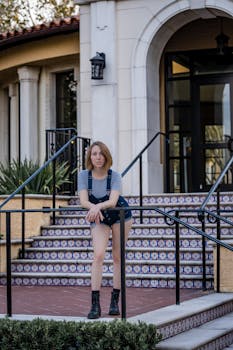Confident woman in casual attire poses on patterned tiled steps outdoors.