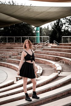 Young woman poses in a moody outdoor amphitheater, showcasing a casual fashion style.