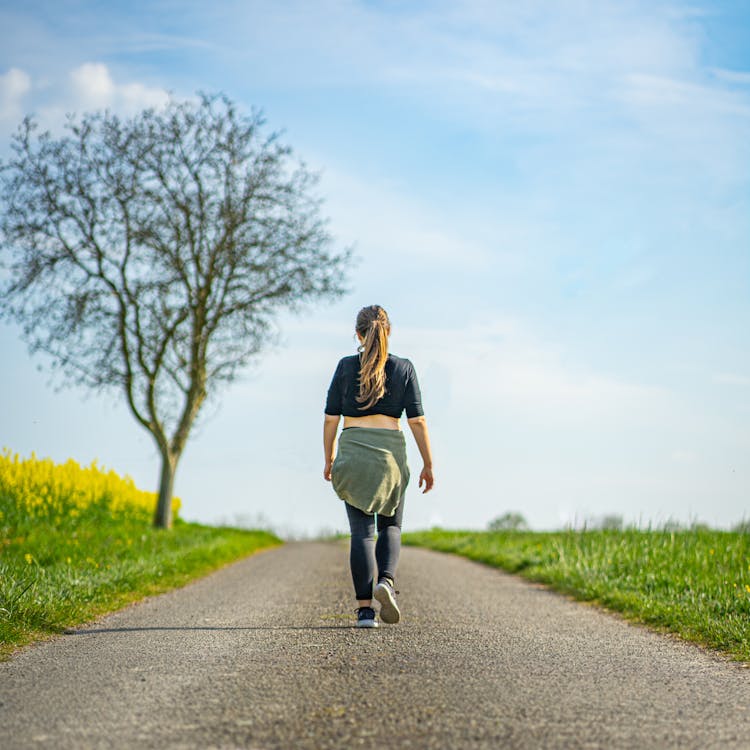 A Woman Walking On Concrete Pathway