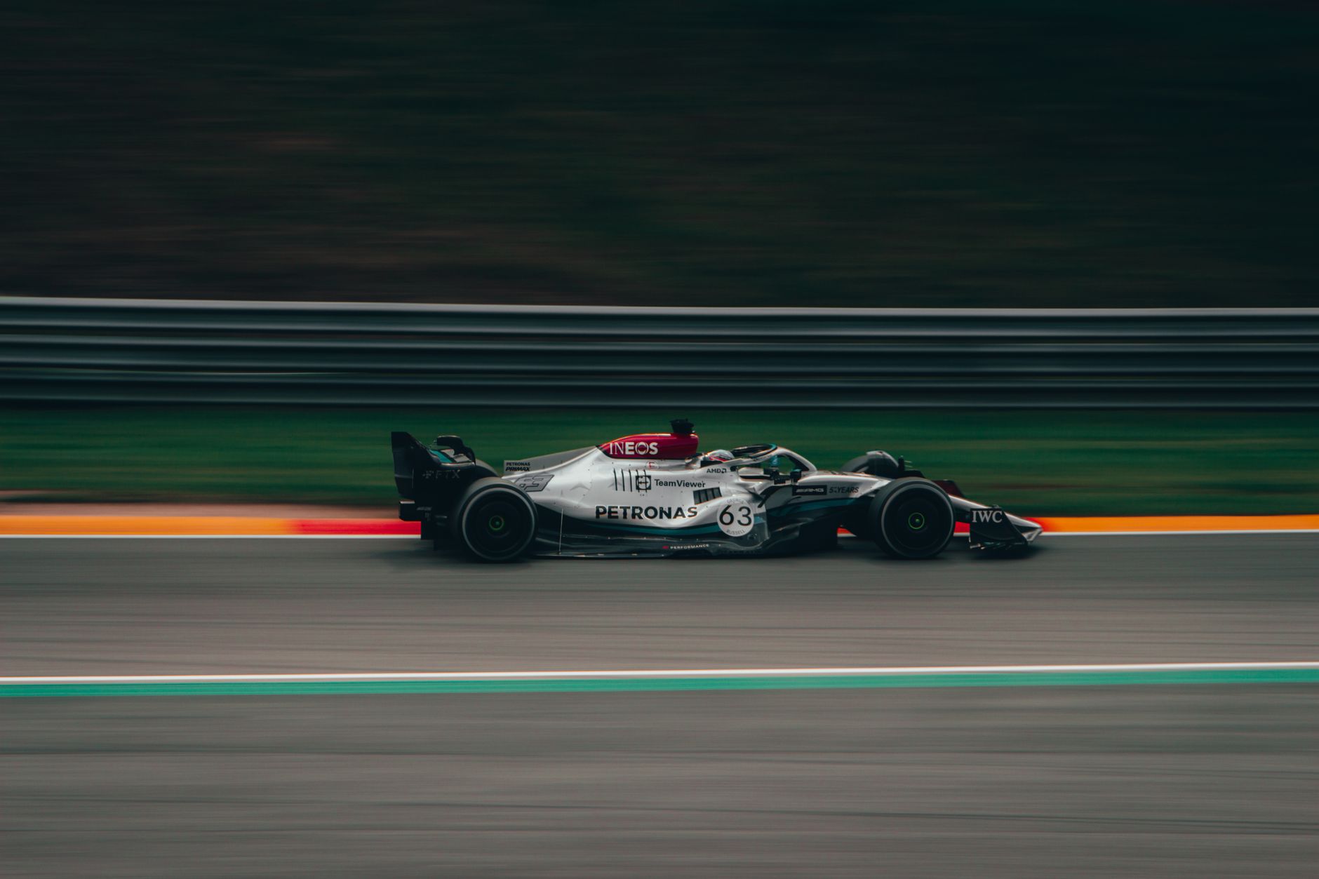 Zijaanzicht van een Formule 1-auto die met hoge snelheid over het racecircuit rijdt, en de beweging en spanning vastlegt.