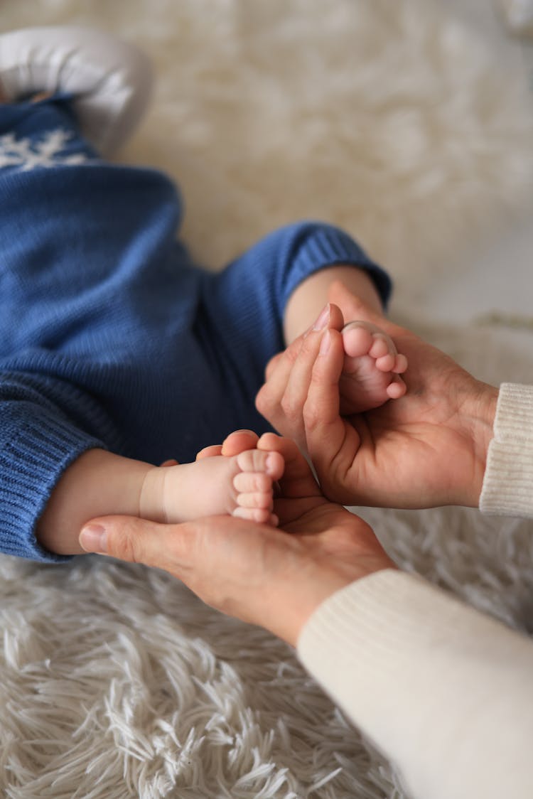 Close-up Of Mother Holding Feet Of Her Little Baby 