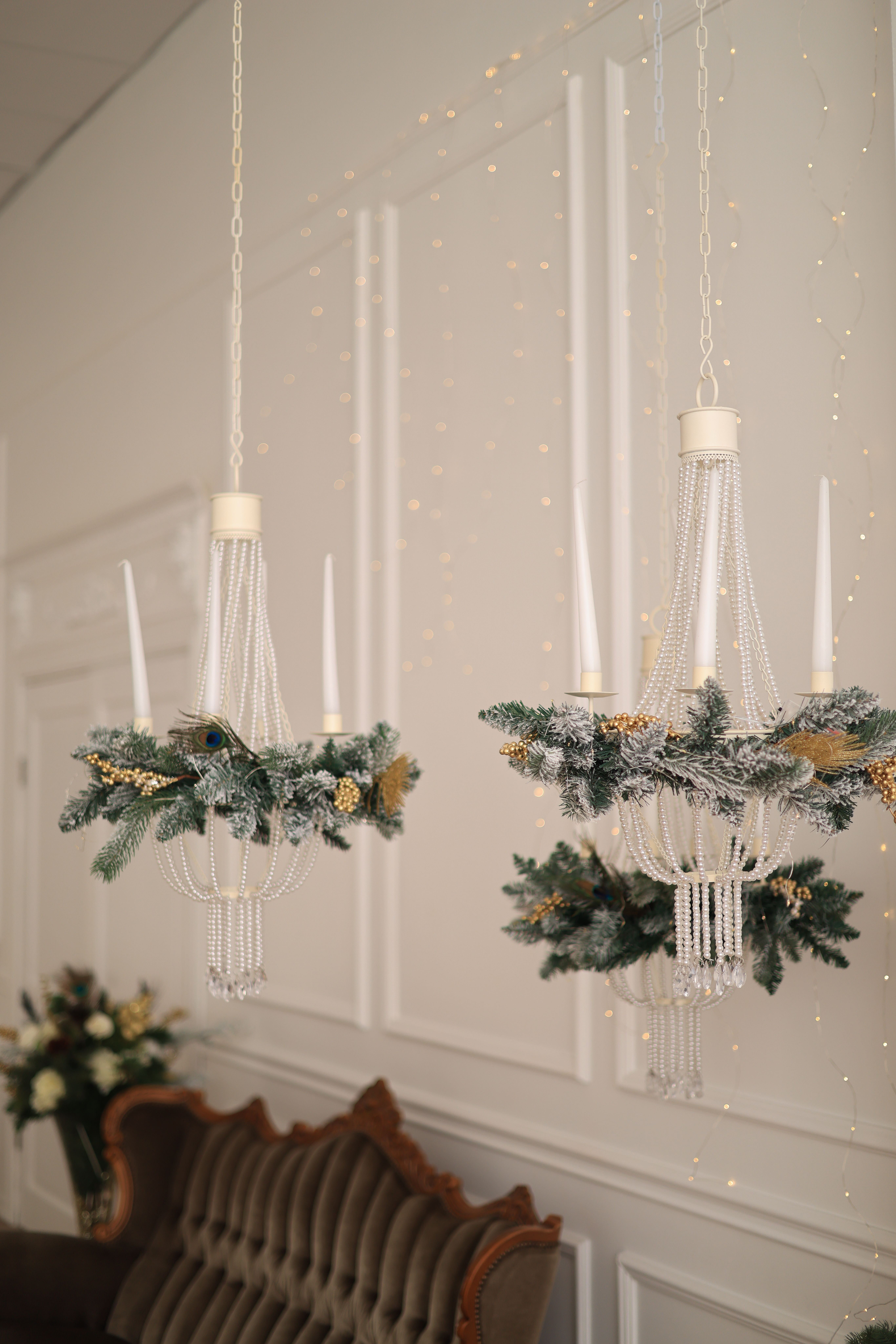 Sophisticated chandeliers adorned with Christmas greenery and ornaments, creating a festive indoor ambiance.