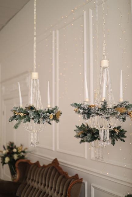 Sophisticated chandeliers adorned with Christmas greenery and ornaments, creating a festive indoor ambiance.