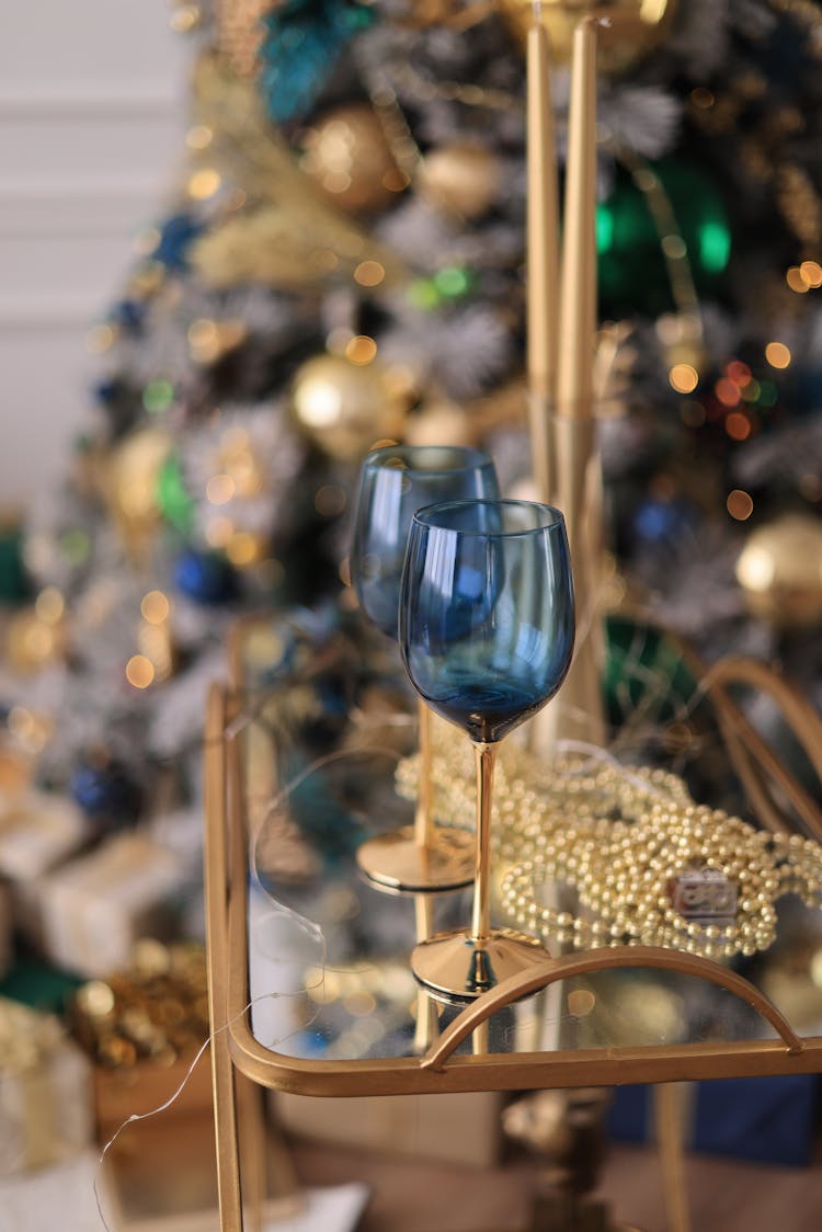 Blue Wineglasses On A Table And Christmas Tree In The Background 