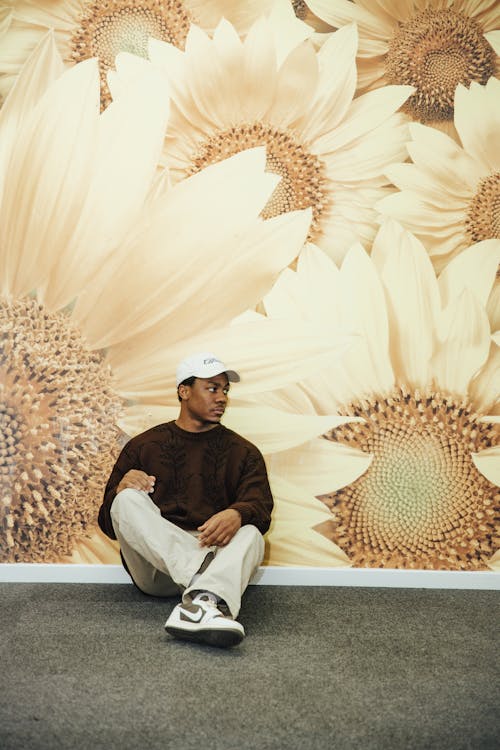 Man in Brown Sweater Sitting Beside a Wall painting