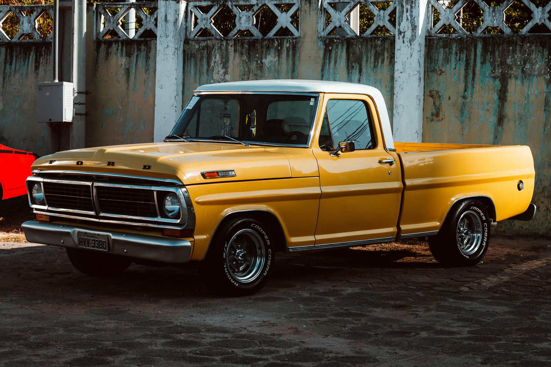 Vintage yellow Ford pickup truck parked against a concrete wall in Fortaleza, Brazil.