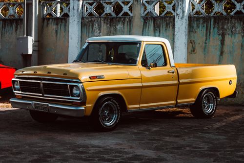 Free Vintage yellow Ford pickup truck parked against a concrete wall in Fortaleza, Brazil. Stock Photo