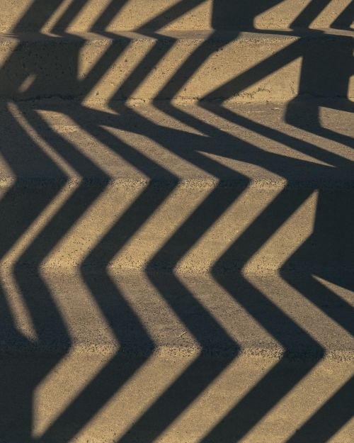 Free Geometric shadows create a striking pattern on concrete stairs, offering a visual play of light and form. Stock Photo