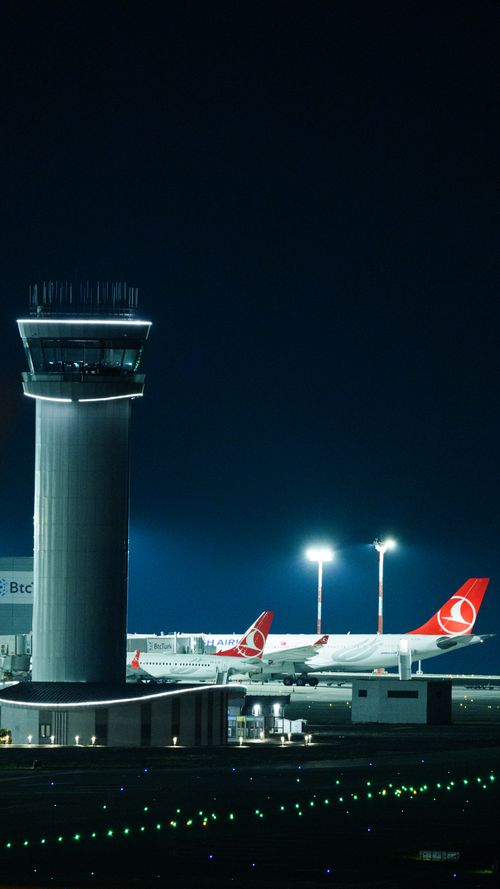 Free Illuminated control tower and Turkish Airlines planes at Istanbul Airport during nighttime. Stock Photo