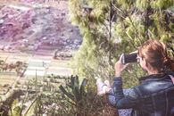 Woman Holding Smartphone Overlooking Plain Field