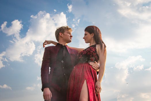 一对身着红色服装的时尚情侣在阳光明媚的蓝天下相拥，展现出优雅的现代感