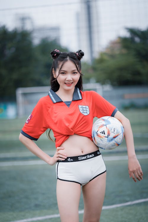 Woman in Red Soccer Jersey Holding a Ball