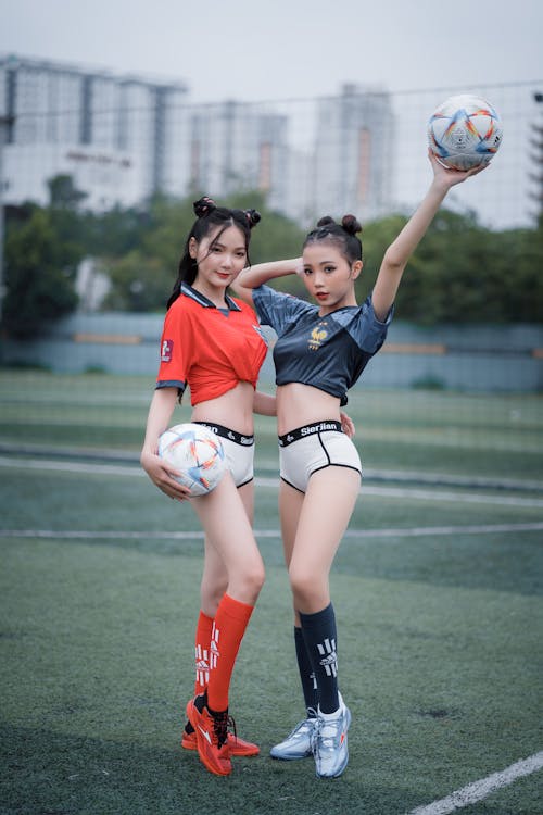 Young Women in a Skimpy Outfits Posing on a Football Pitch 