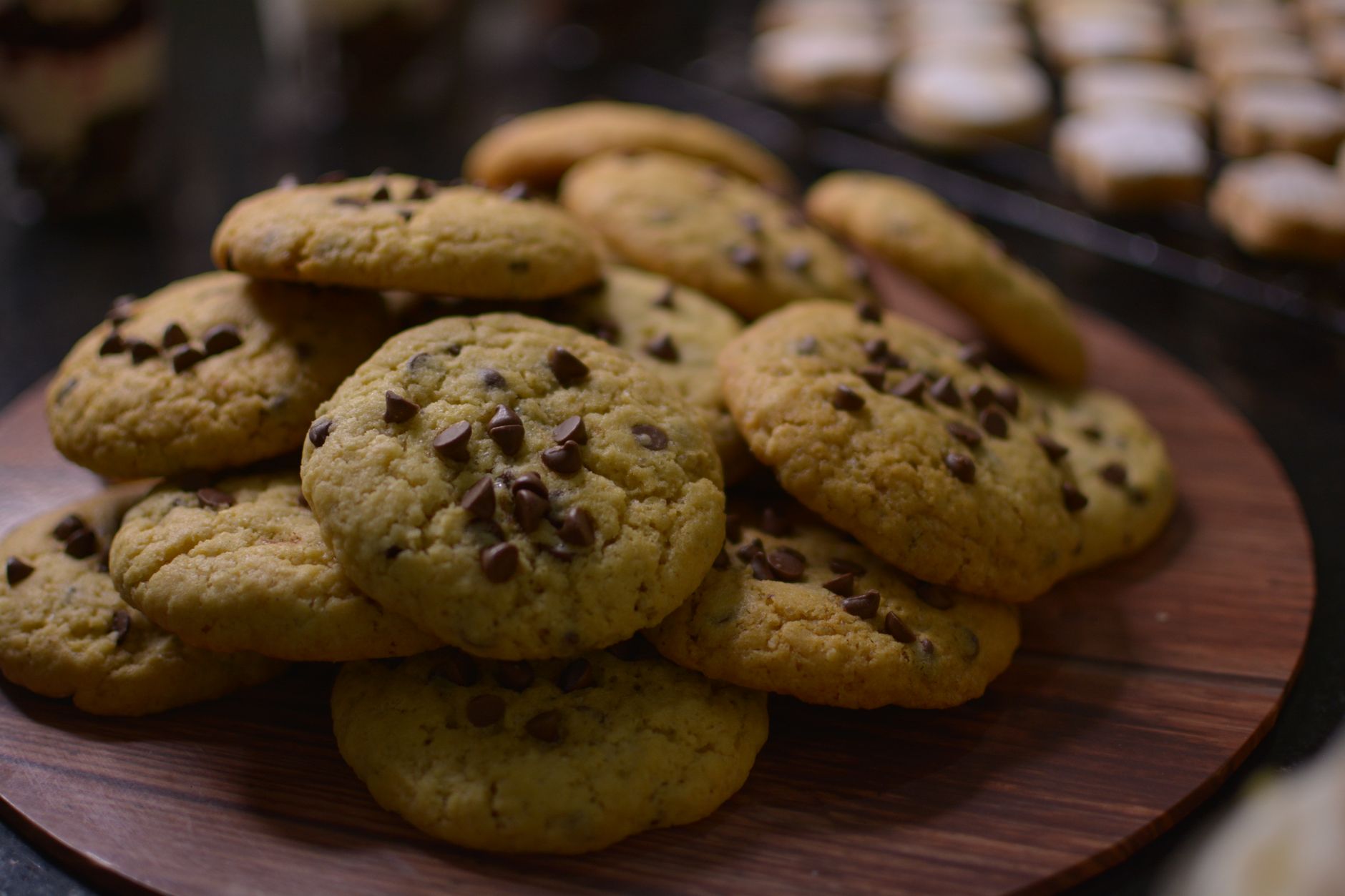 Close-up view of freshly baked chocolate chip cookies on a wooden tray.