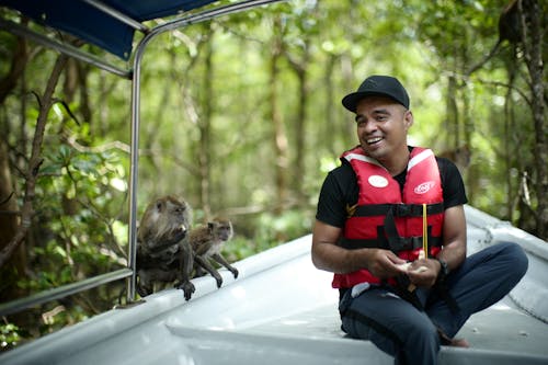 Smiling Man Sitting by Macaques