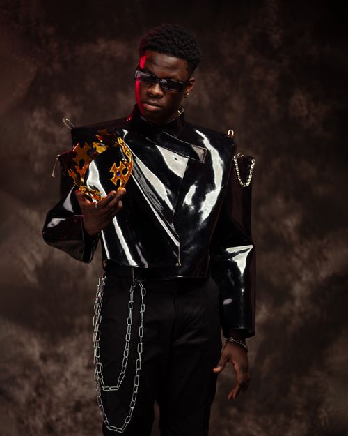 Free Fashionable portrait of a model in a black leather jacket, holding a unique metallic crown during a studio shoot. Stock Photo