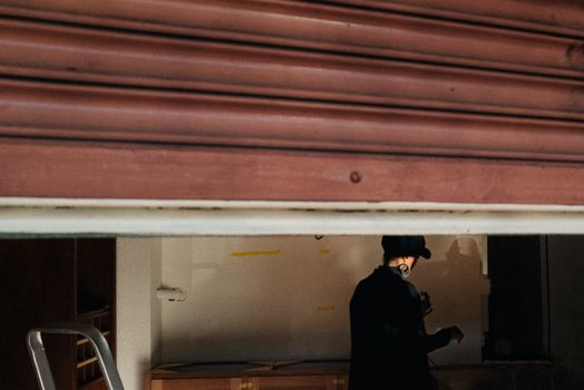 Woman in Cap in Garage with Open Gates
