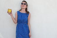 一位身着圆点连衣裙的时尚女士，在阳光明媚的日子里喝着咖啡，尽显无忧无虑的生活方式