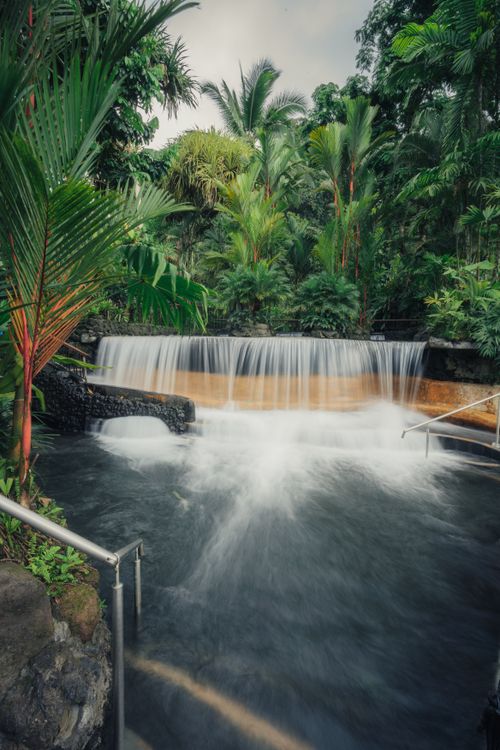 Free Tranquil waterfall cascading in a tropical jungle setting, surrounded by lush greenery and vibrant foliage. Stock Photo