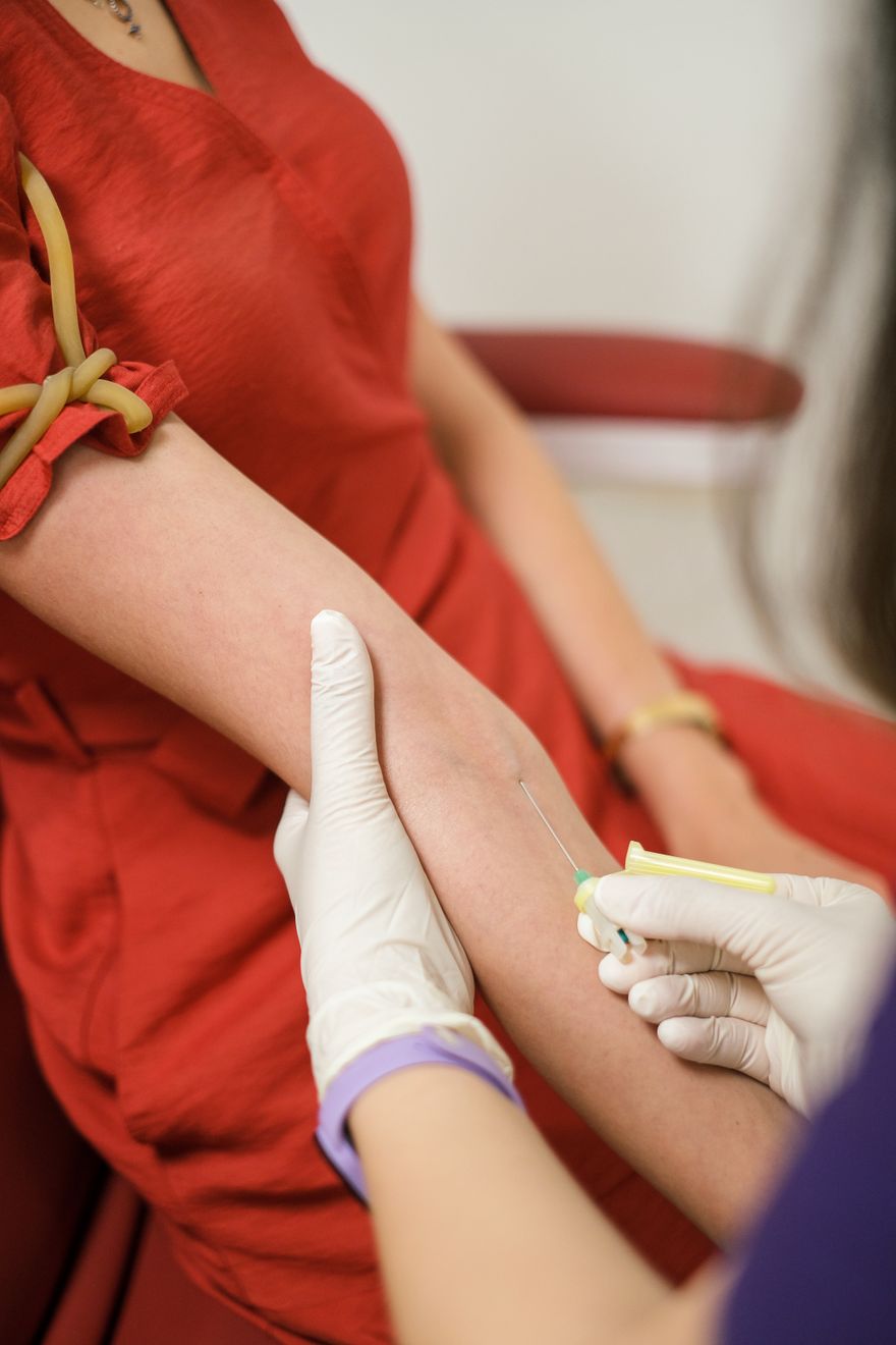 A clinician draws a blood sample from a seated patient. Photo by Yunus Tuğ on Pexels