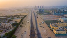 从鸟瞰图可以看到迪拜的城市扩张，包括日落时分的建筑和沙漠道路