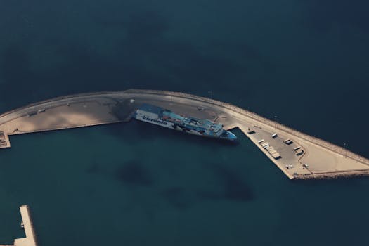 Aerial perspective of a cargo ship docked in a tranquil harbor, ideal for maritime themes.