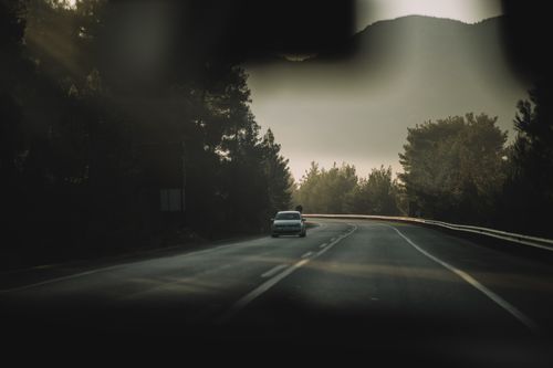 Free A lone car drives along a foggy road surrounded by trees, capturing a peaceful highway scene in Turkey. Stock Photo